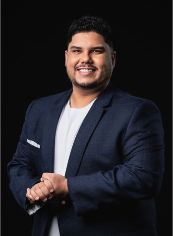 Um homem de 30 e poucos anos, cabelo preto, pele branca sorrindo para a foto